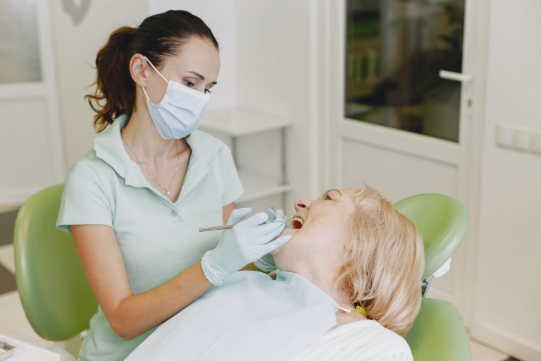 Dentist looking her old patient with tools